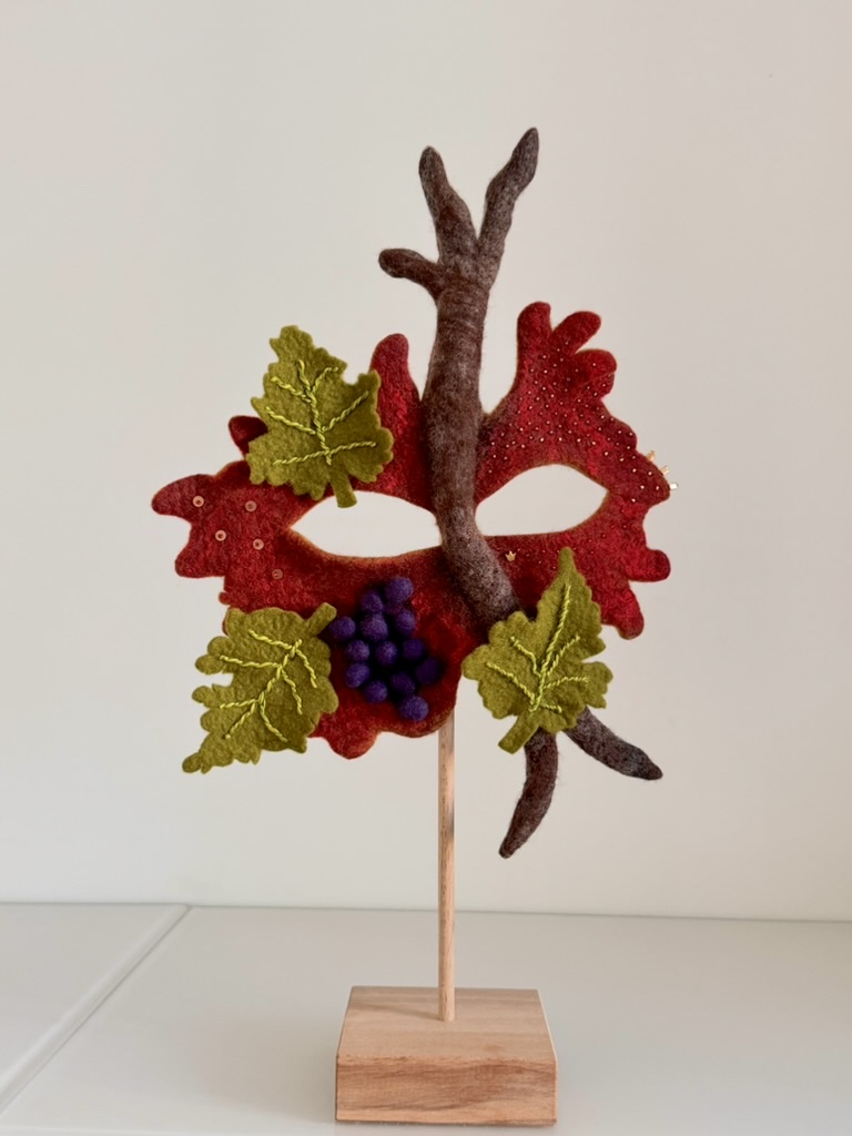 Handgefilzte Maske „Die Weinkönigin“ in Weinrot mit gefilzter Rebe, grünen bestickten Weinblättern und einer Traube aus violetten Filzbeeren